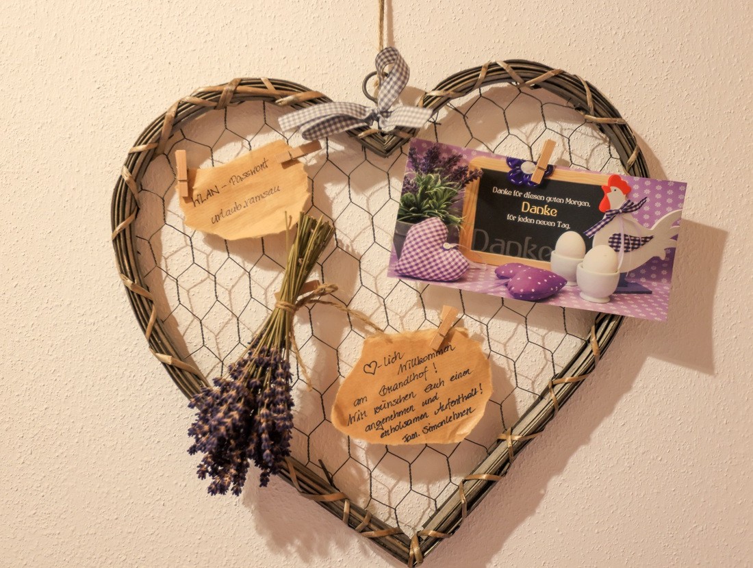 Herzförmiger Korb an der Wand mit Lavendel, Zettel und Foto verziert