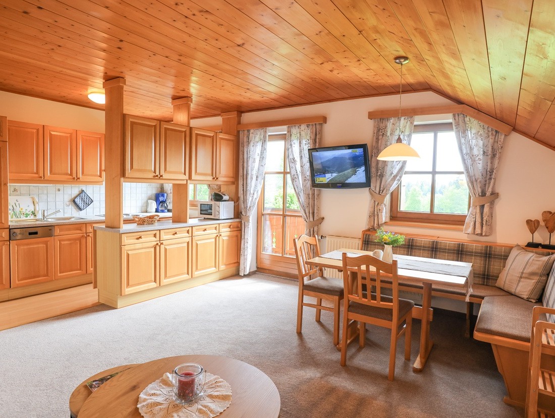Gemütliche Holzküche mit Esstisch und Sofa in einer hellen Dachwohnung