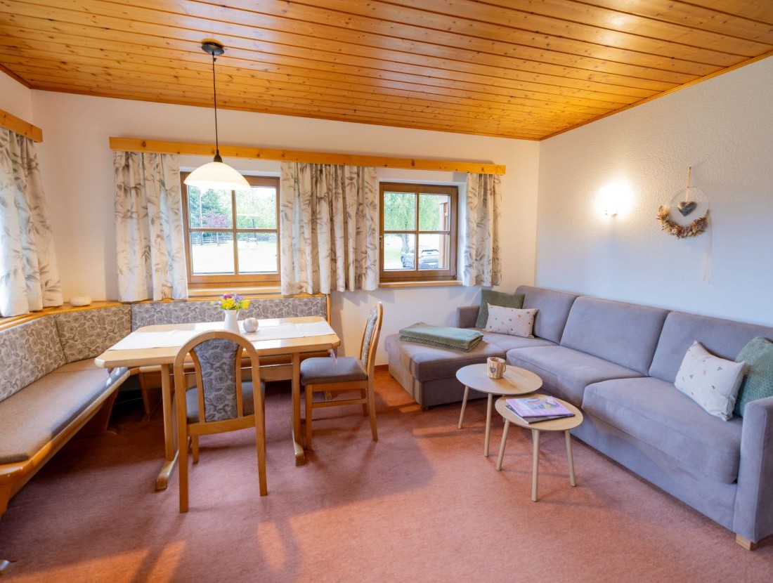 Gemütliches Wohnzimmer mit Ecksofa, Esstisch und Holzdecke