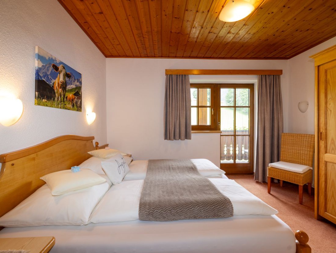 Gemütliches Schlafzimmer mit Holzmöbeln, Doppelbett und Fenster mit Blick auf die Natur