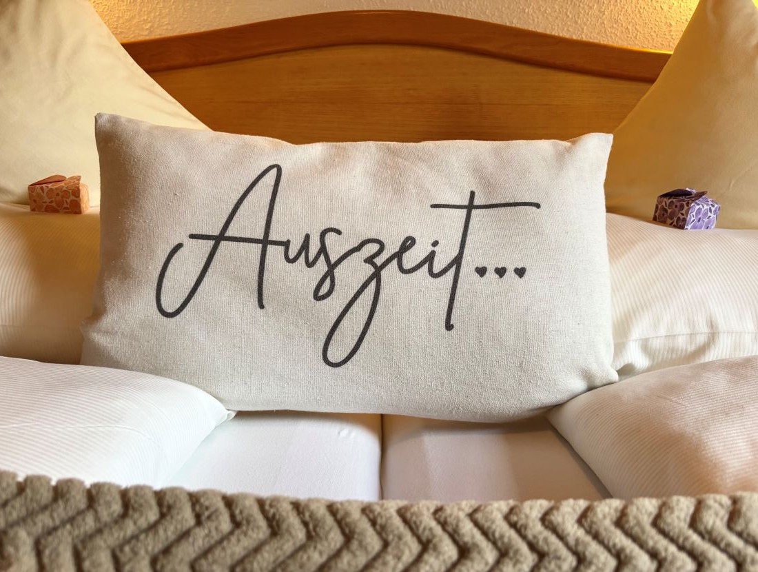 Kissen auf einem Bett mit der Aufschrift "Auszeit..."